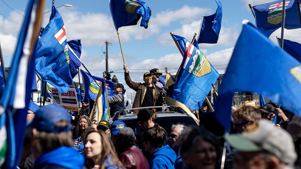 Mitch Sylvestre submitting signatures with supporters flying flags in Edmonton