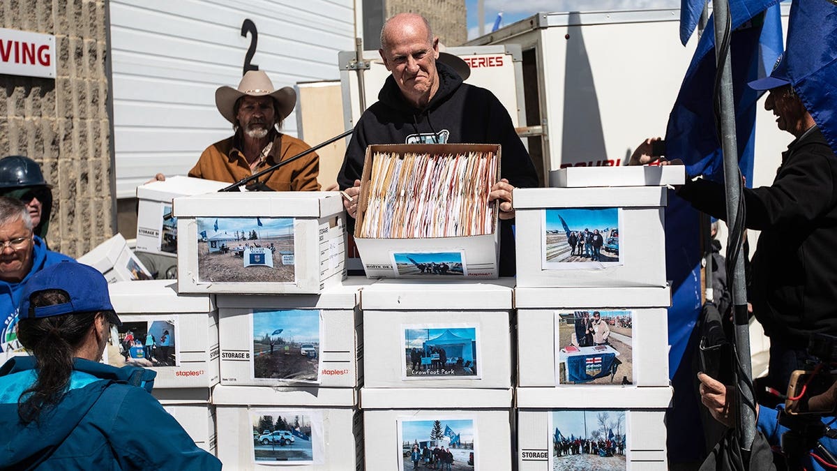 Mitch Sylvestre holding boxes of signatures inside Elections Alberta office in Edmonton