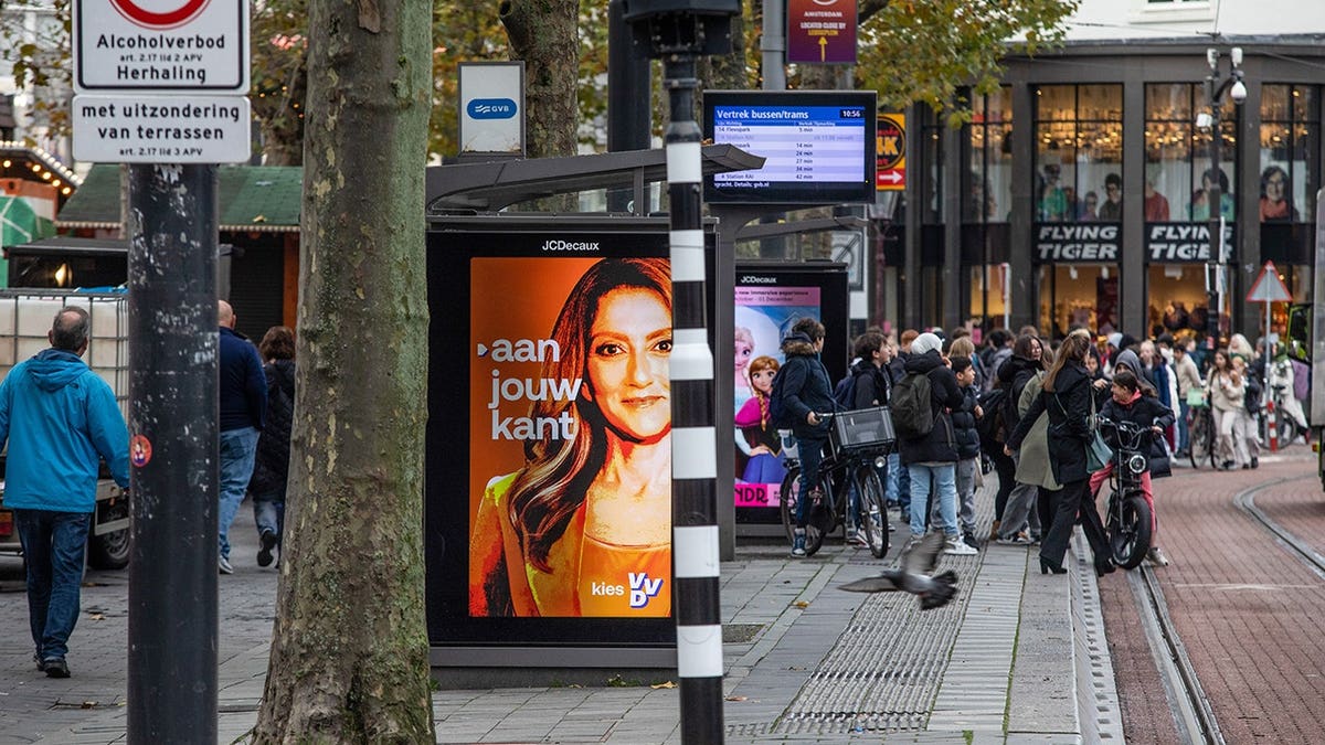 An advertisement is displayed at a tram stop in Amsterdam, Netherlands