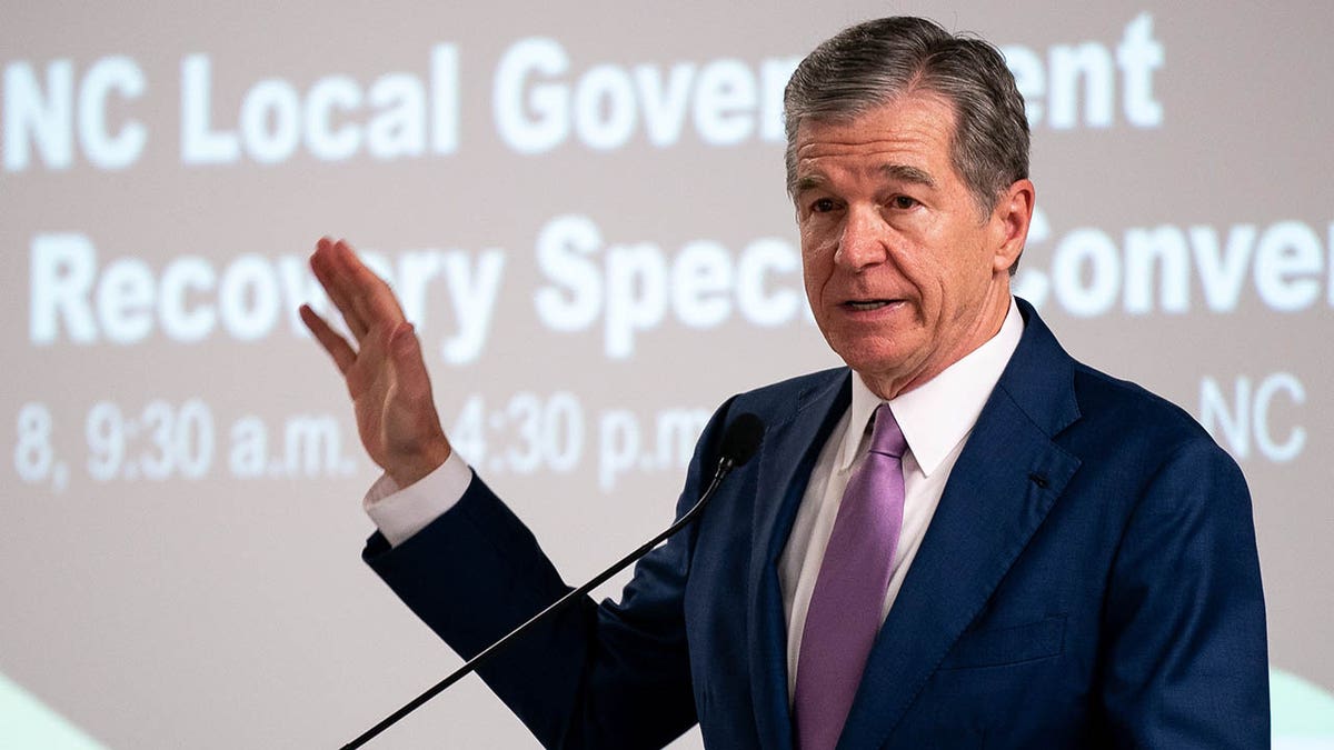 North Carolina Governor Roy Cooper speaking at a conference center podium