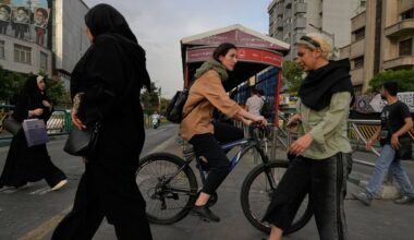 A woman rides a bicycle as others cross a street in downtown Tehran, Iran, Sunday, May 24, 2026. (AP Photo/Vahid Salemi)