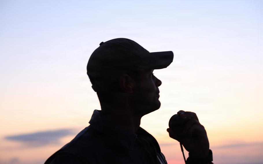 A silhouette of a sailor watching a missile.