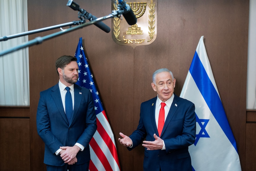 Men in dark suits — JD Vance and Benjamin Netanyahu — stand in front of an Israeli flag and a US flag.