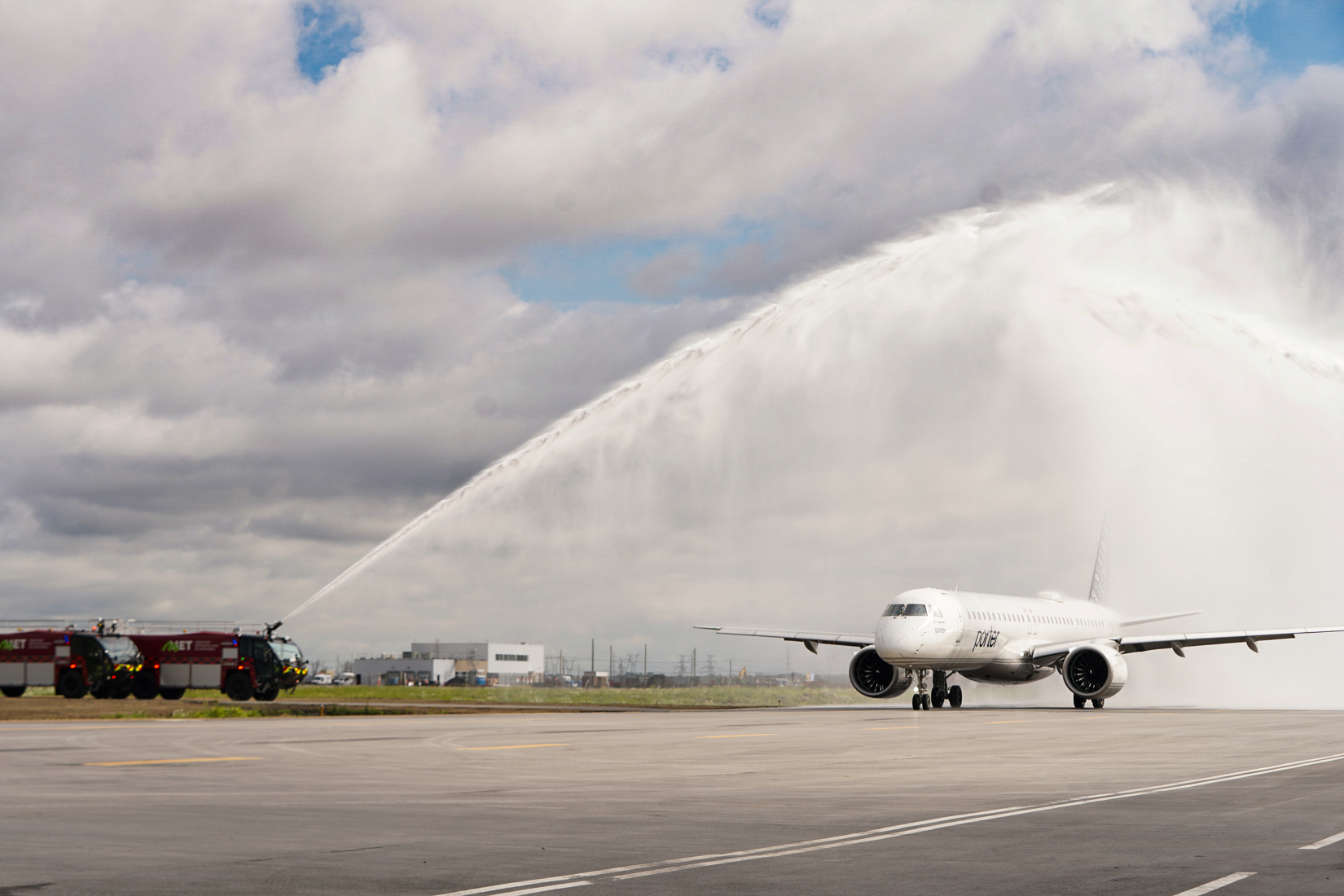 Water cannons spray over an airplane on a runway.