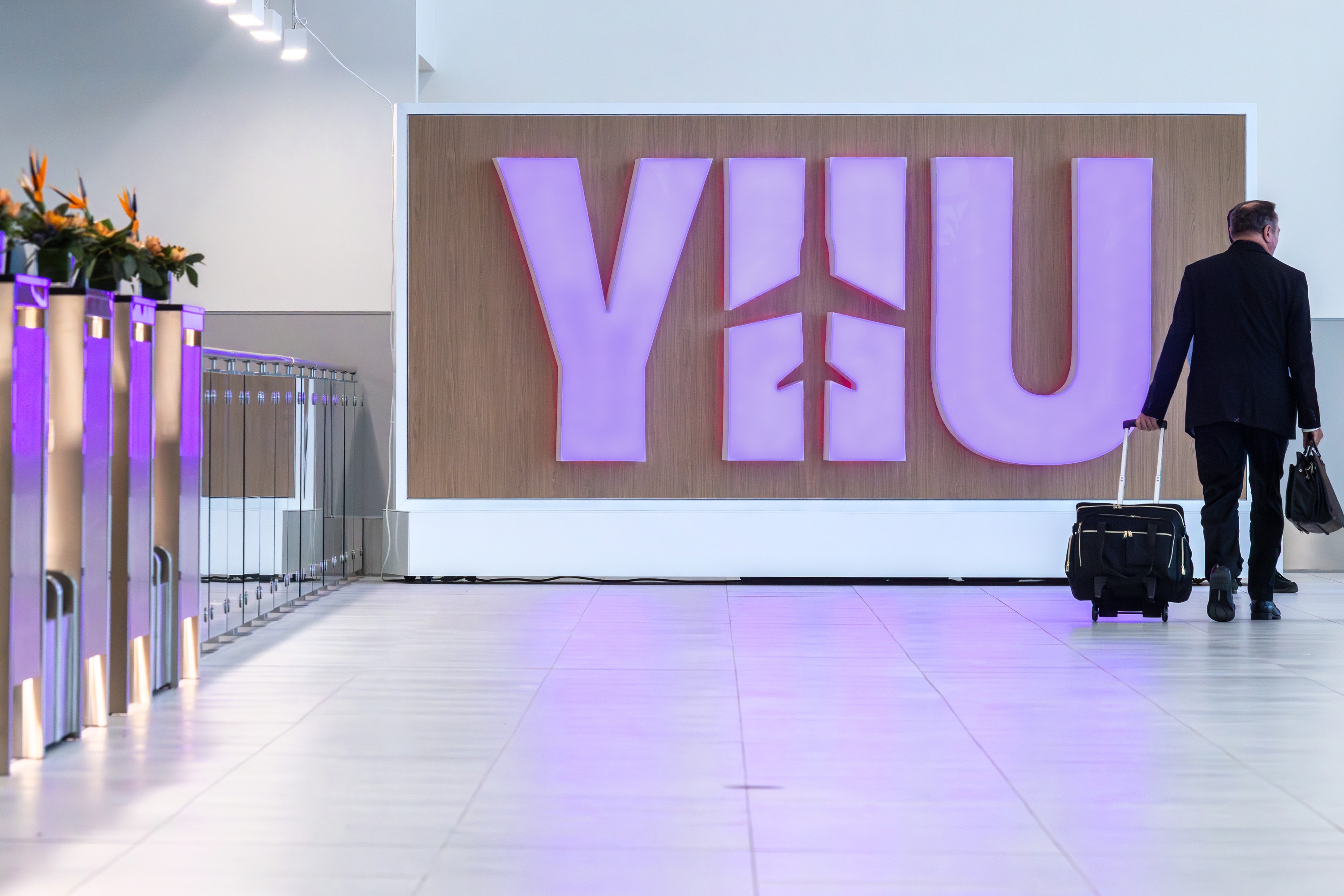 A man wheels a suitcase past a sign reading YHU at the new Montreal Metropolitan Airport.