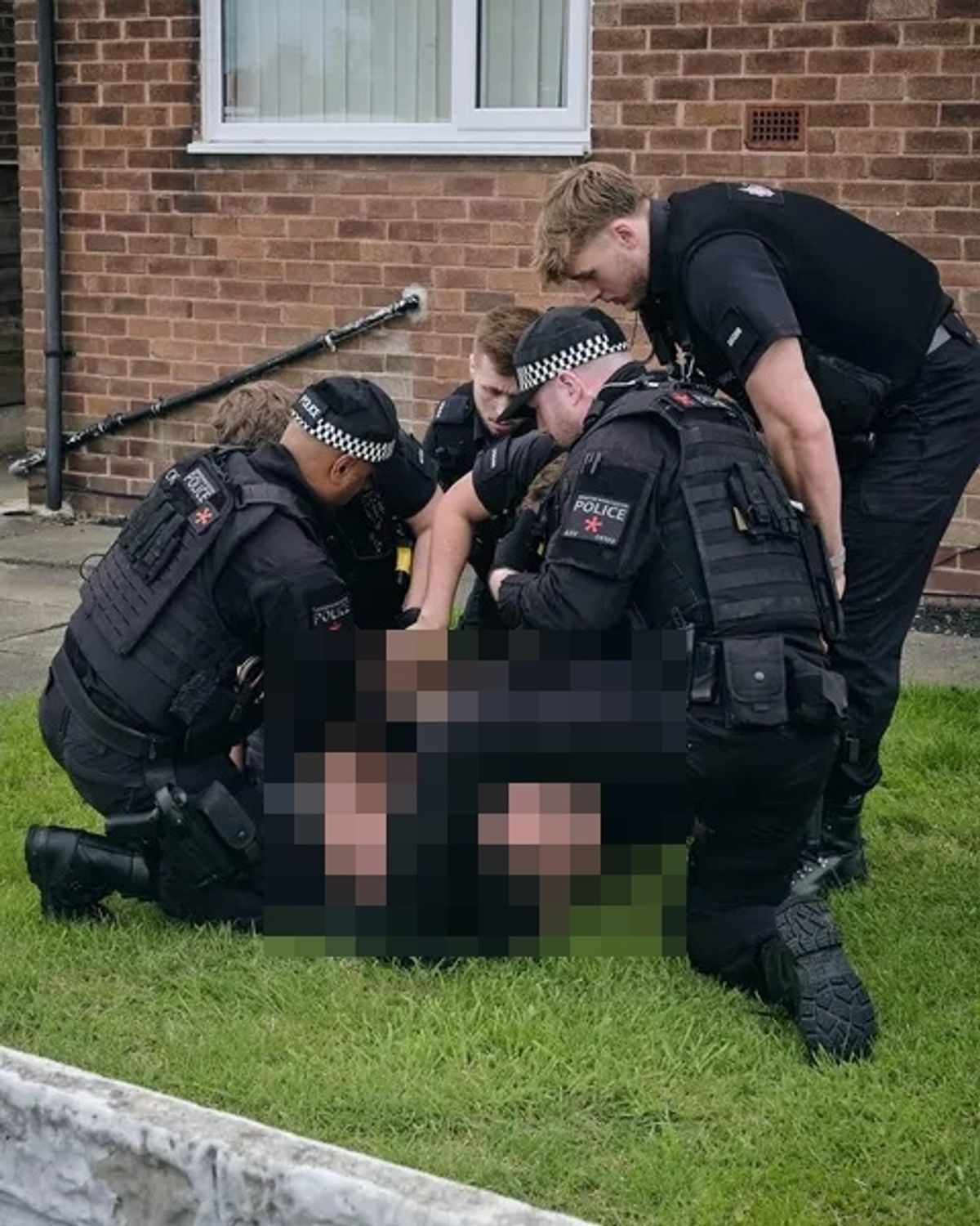 A man is detained by police on Rake Lane
