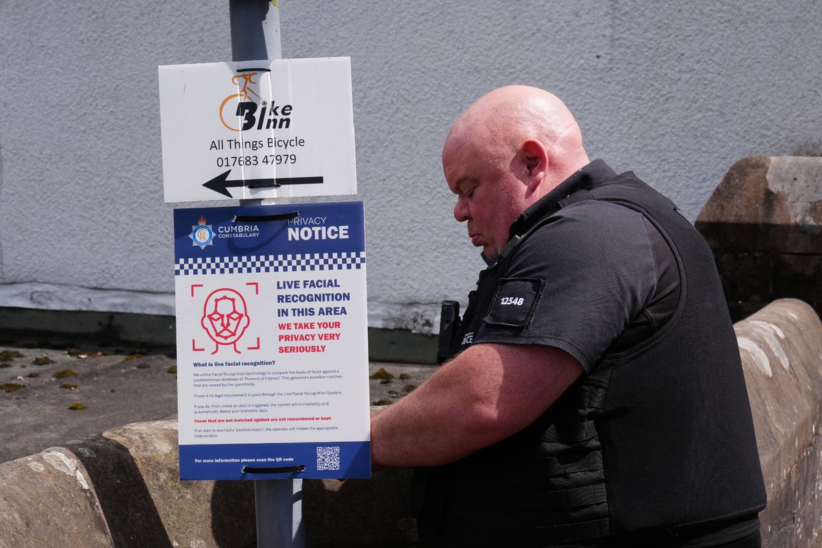 A police officer putting up a sign about live facial recognition during the Appleby Horse Fair