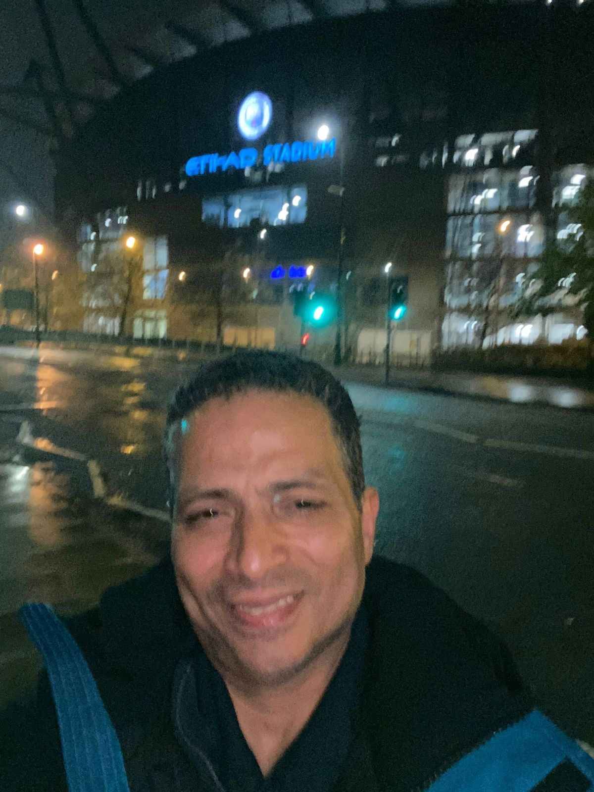 Mohamed smiling with the sign for Manchester City's Etihad Stadium in the background