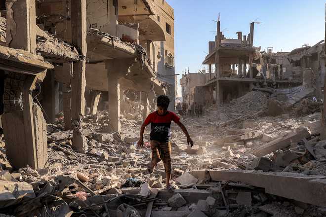TOPSHOT-PALESTINIAN-ISRAEL-CONFLICT-GAZA A boy walks through the rubble of a building that was destroyed following Israeli bombardment after an evacuation order, at the Maghazi camp for Palestinian refugees in the central Gaza Strip on June 12, 2026.