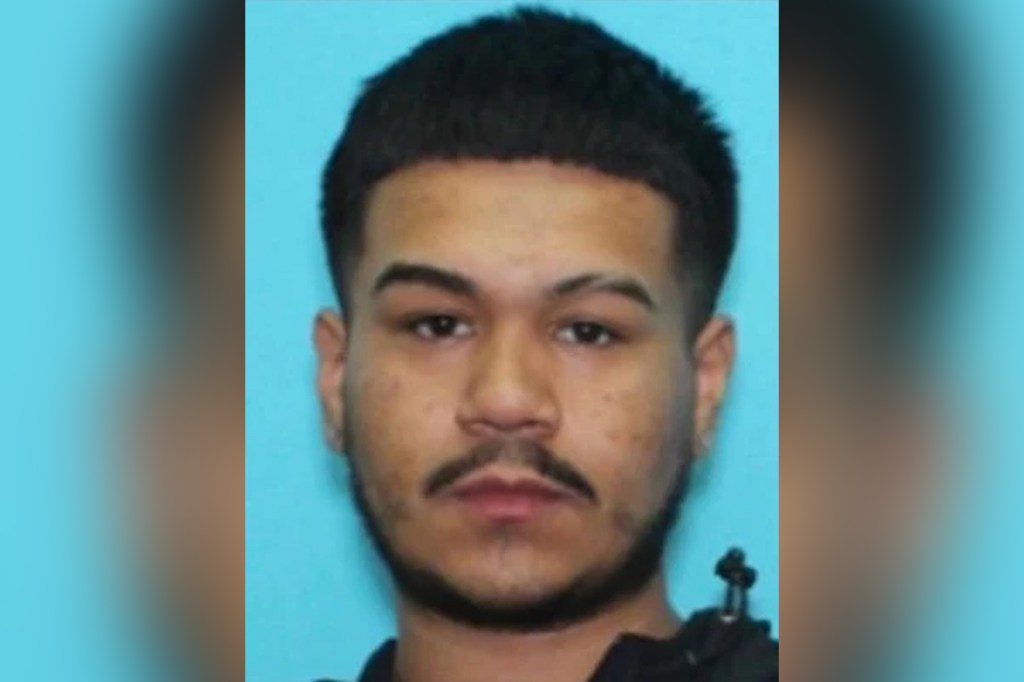 Mugshot of a young man with dark hair, a mustache, and a short beard.