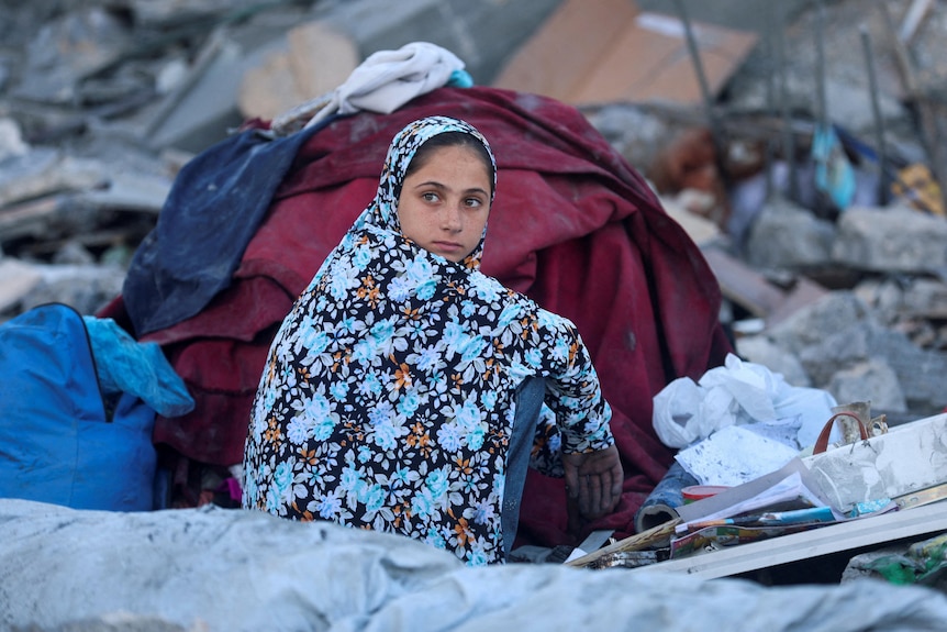 A little girl sitting on a pile of rubble