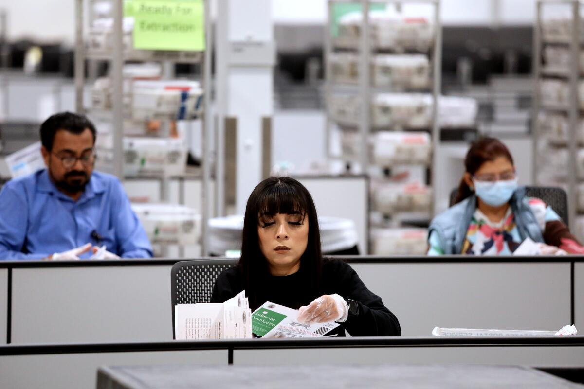 An election worker separates ballots from vote by mail envelopes to be tallied at a Ballot Processing Center