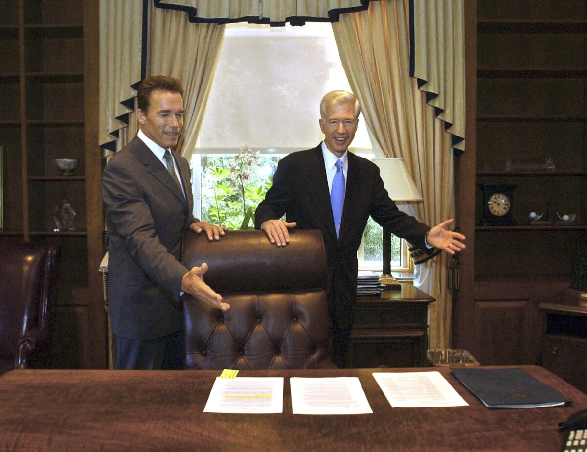 Arnold Schwarzenegger, left, and Gray Davis joke with each other in the governor's private office