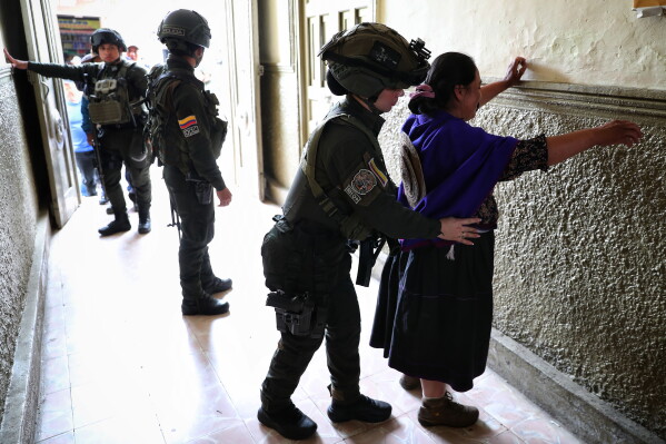 Police frisk voters arriving to a polling station during presidential election in Silvia, Colombia, Sunday, May 31, 2026. (AP Photo/Santiago Saldarriaga)