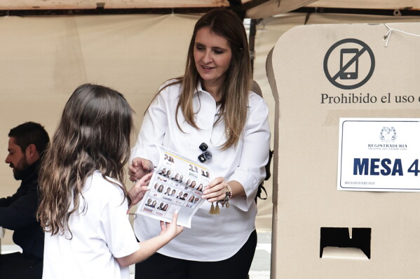 Presidential candidate Paloma Valencia of the Democratic Center party shows her ballot to her daughter during the presidential election in Bogota, Colombia, Sunday, May 31, 2026. (AP Photo/Jose Vargas)