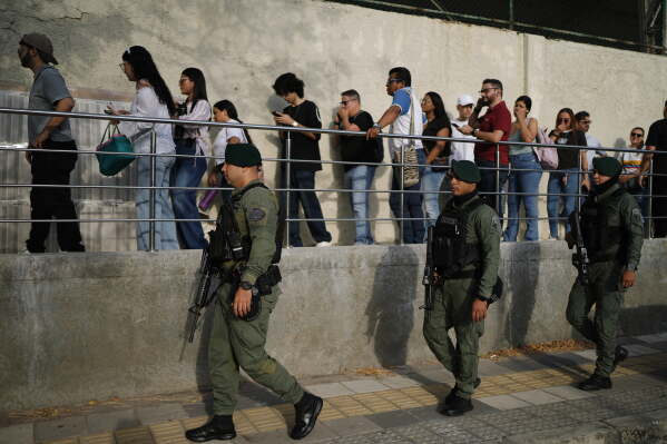 Soldiers patrol as voters arrive at a polling station during the presidential election in Barranquilla, Colombia, Sunday, May 31, 2026. (AP Photo/Ivan Valencia)