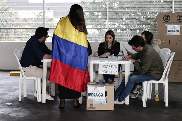 A woman wrapped in a Colombian flag votes during the presidential election in Bogota, Colombia, Sunday, May 31, 2026. (AP Photo/Jose Vargas)