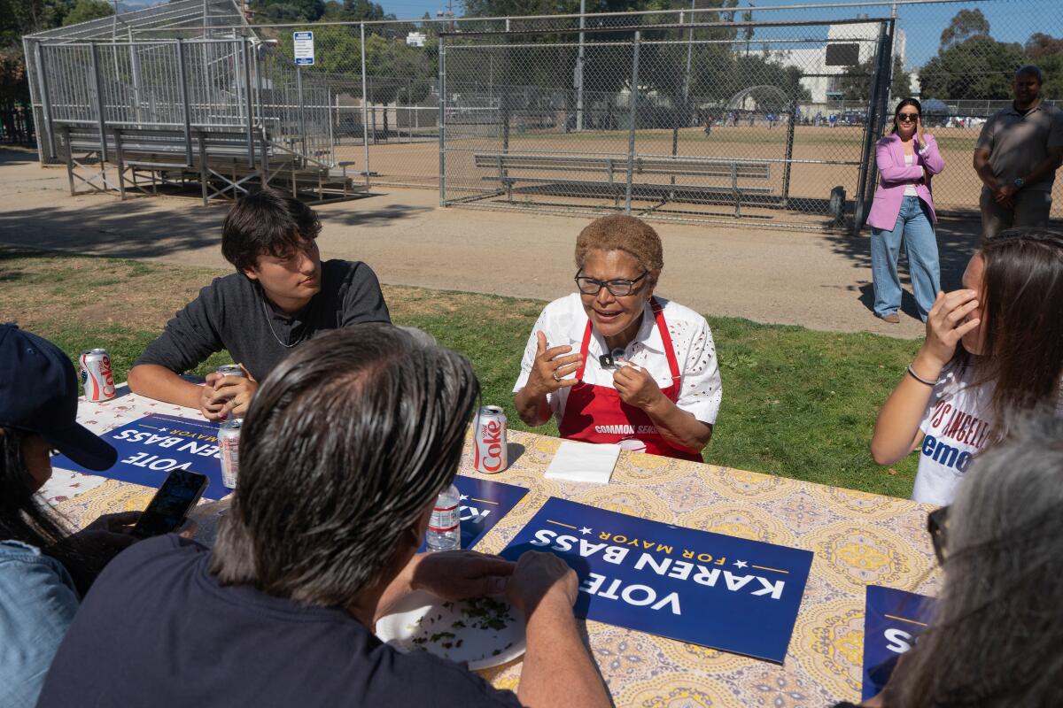Los Angeles Mayor Karen Bass speaks to people in front of signs.