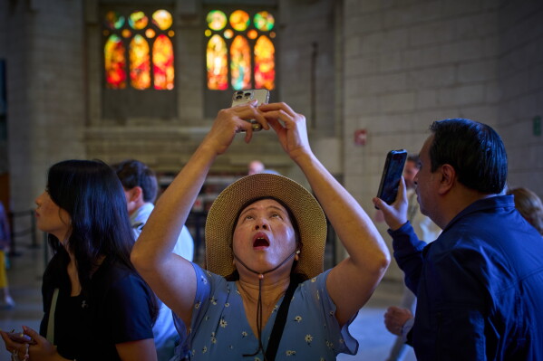 Visitors take photos inside Antoni Gaudí's Basilica of the Sagrada Familia in Barcelona, Spain, Tuesday, May 26, 2026, ahead of Pope Leo XIV's visit to the city in June. (AP Photo/Emilio Morenatti)