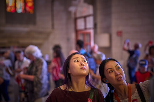 Visitors gaze upward inside the Basilica of the Sagrada Familia in Barcelona, Spain, Tuesday, May 26, 2026, as Antoni Gaudí's unfinished masterpiece prepares for Pope Leo XIV's visit to the city in June. (AP Photo/Emilio Morenatti)