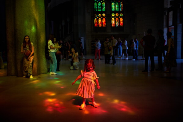 A girl plays inside Antoni Gaudí's Sagrada Família basilica illuminated in colored light from its stained-glass windows in Barcelona, Spain, Tuesday, May 26, 2026, ahead of Pope Leo XIV's visit to the city in June. (AP Photo/Emilio Morenatti)