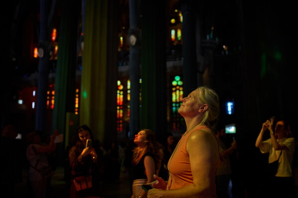 A visitor looks up inside Antoni Gaudí's Basilica of the Sagrada Familia illuminates by colored light from its stained-glass windows in Barcelona, Spain, Tuesday, May 26, 2026, ahead of Pope Leo XIV's visit to the city in June. (AP Photo/Emilio Morenatti)