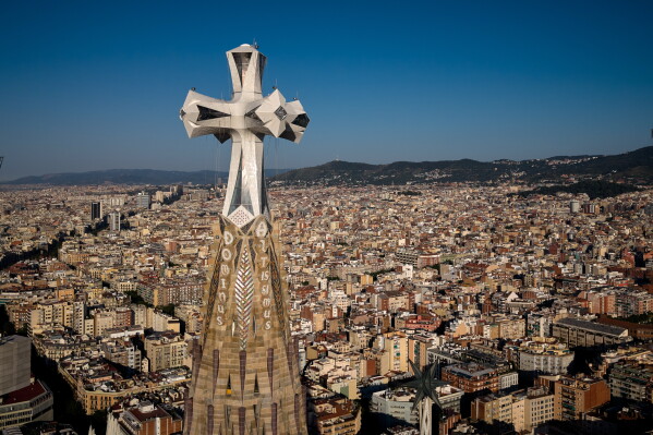 A cross crowns the 172.5-meter (566-foot) Tower of Jesus Christ at the Sagrada Familia basilica in Barcelona, Spain, Thursday, May 28, 2026, ahead of Pope Leo XIV's visit to the city in June. (AP Photo/Emilio Morenatti)