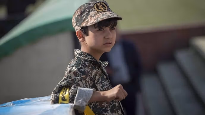A child dressed in a military-style uniform attends a public gathering in Iran.
