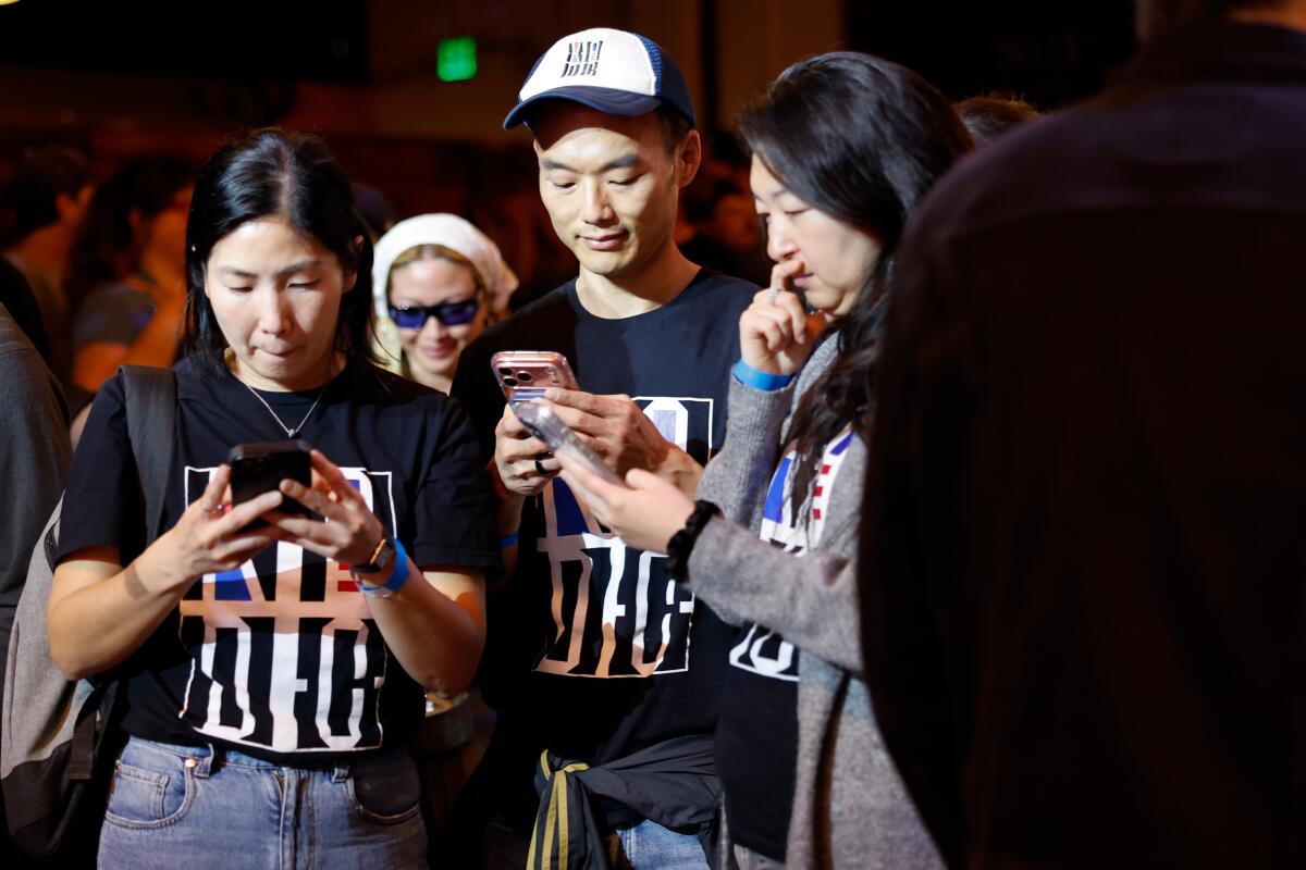Supporters watch election results come in on their phones during Nithya Raman's election night party