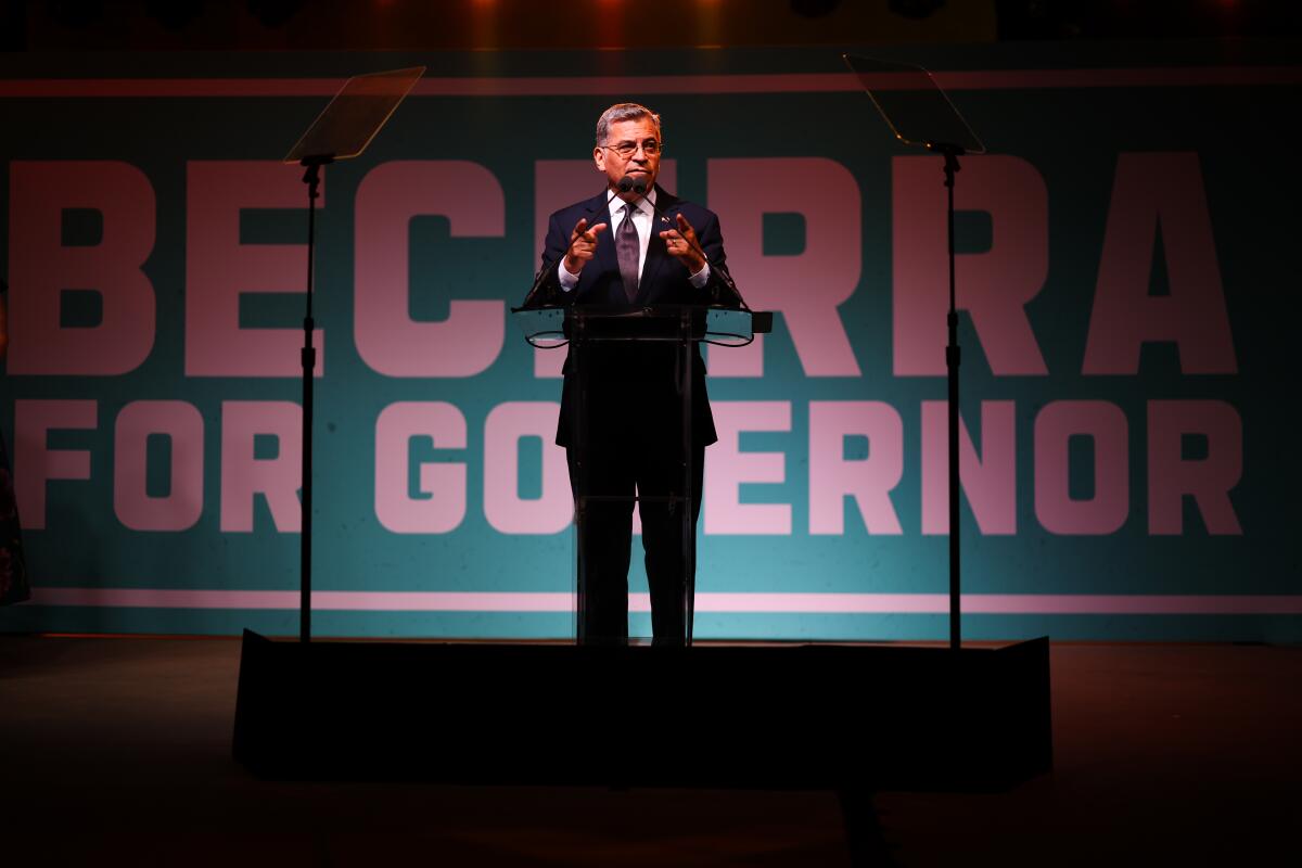 Xavier Becerra speaks during an election night event with Becerra for Governor on a large sign behind him.