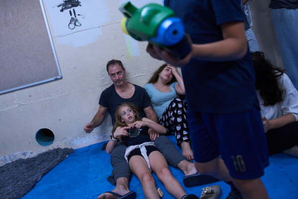 People take shelter as air raid sirens warning of incoming Iranian missiles in Ramat Gan, Israel, Monday, June 8, 2026. (AP Photo/Oded Balilty)