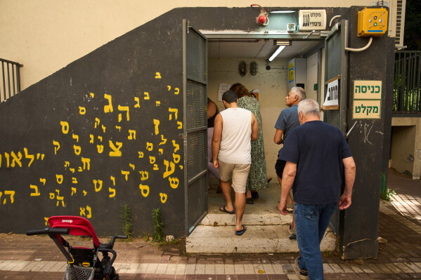 People take shelter as air raid sirens warning of incoming Iranian missiles in Ramat Gan, Israel, Monday, June 8, 2026. (AP Photo/Oded Balilty)