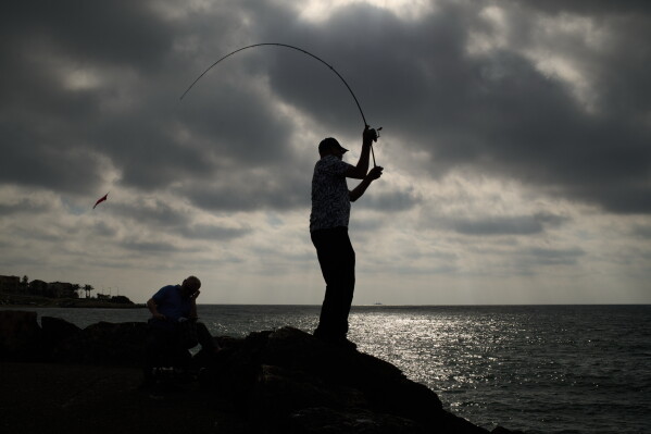 A man casts his fishing rod into the Mediterranean Sea as he stands on the beachfront in Haifa, northern Israel, Monday, June 8, 2026. (AP Photo/Leo Correa)
