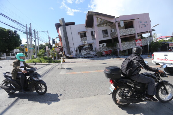 People on motorcycles pass by a collapsed structure after an earthquake in General Santos, Philippines on Monday, June 8, 2026. (AP Photo)