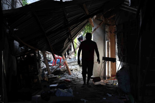 A resident walks past debris from damaged houses following an earthquake in General Santos, Philippines Tuesday, June 9, 2026. (AP Photo/Basilio Sepe)