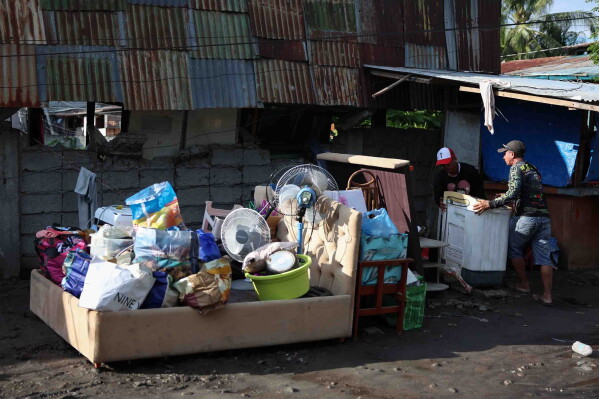 Residents save their belongings as they evacuate from their damaged houses following an earthquake in General Santos, Philippines Tuesday, June 9, 2026. (AP Photo/Basilio Sepe)