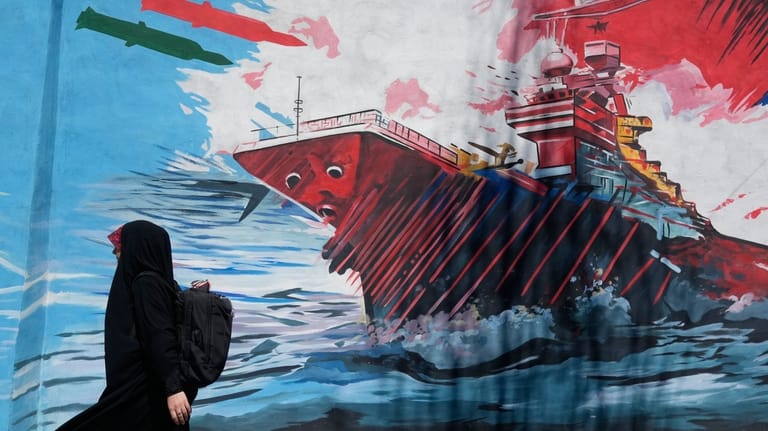 A woman walks past a mural depicting a U.S. aircraft...