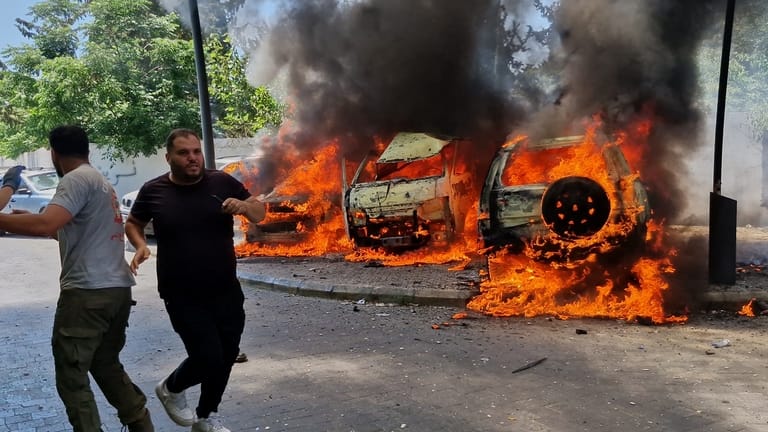 A man runs past burning cars following an Israeli airstrike...