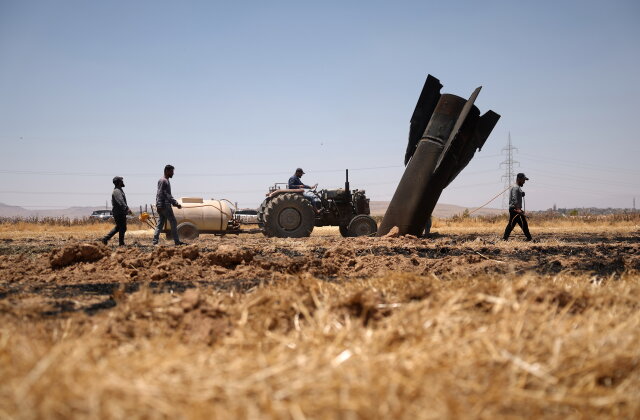 Farmers spray water in a burned agricultural field next to a projectile near the town of Najha, Syria, Monday, June 8, 2026, after debris from Iranian missile launches during the Iran-Israel conflict fell in the area. (AP Photo/Ghaith Alsayed)
