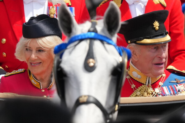 Britain's King Charles III, and Queen Camilla look out from their carriage at the crowds lining The Mall as they return to Buckingham Palace during Trooping The Colour, the King's annual birthday parade, in London, Saturday, June 13, 2026. (AP Photo/Kirsty Wigglesworth)