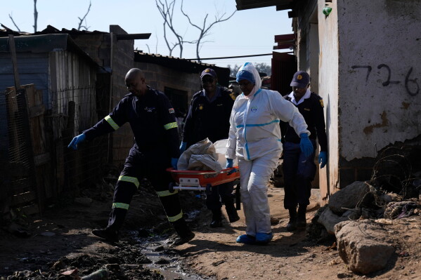 Police officers carry the body of a person on a stretcher after a mass shooting at an informal settlement in the Cleveland suburb of Johannesburg, South Africa, Wednesday, June 10, 2026. (AP Photo/Themba Hadebe)