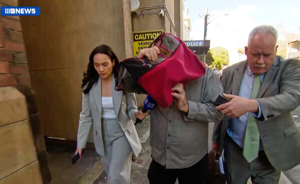 In this image made from video, David James Cook, center, reacts as media attempt to interview him after appearing in a Sydney court and banned from contacting Norway's Princess Ingrid Alexander or her family for two years as she studies at a university in Australia, Wednesday, June 3, 2026. (Channel Nine via AP)