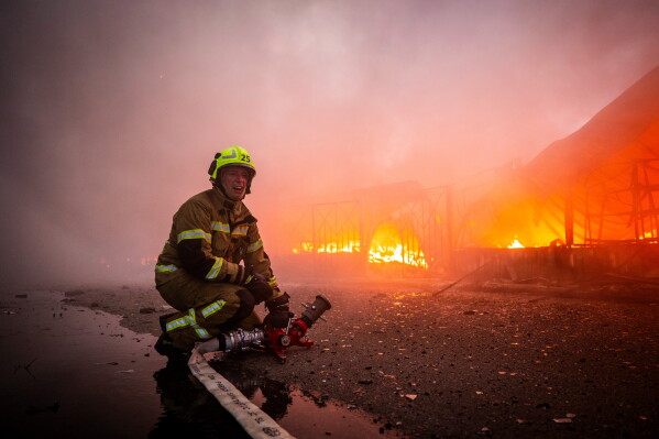 Firefighters try to put out a fire at a city marketplace following a Russian missile and drone attack in Kyiv, Ukraine, Monday, June 15, 2026. (AP Photo/Dan Bashakov)