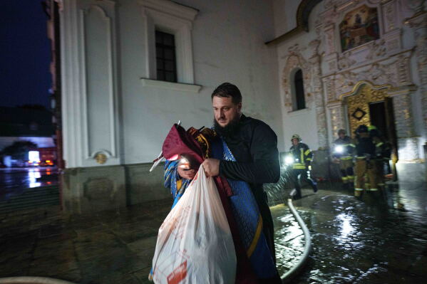 A priest carries church inventory out of the burning Dormition Cathedral of the Kyiv-Pechersk Lavra, also known as the Monastery of the Caves, during a Russian strike on Kyiv, Ukraine, on Monday, June 15, 2026. (AP Photo/Evgeniy Maloletka)