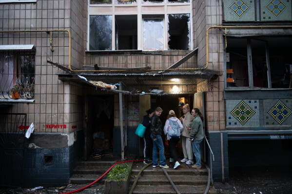 Local residents gather near the entrance to a damaged residential building following an overnight Russian attack in Kyiv, Ukraine, Monday, June 15, 2026. (AP Photo/Danylo Antoniuk)