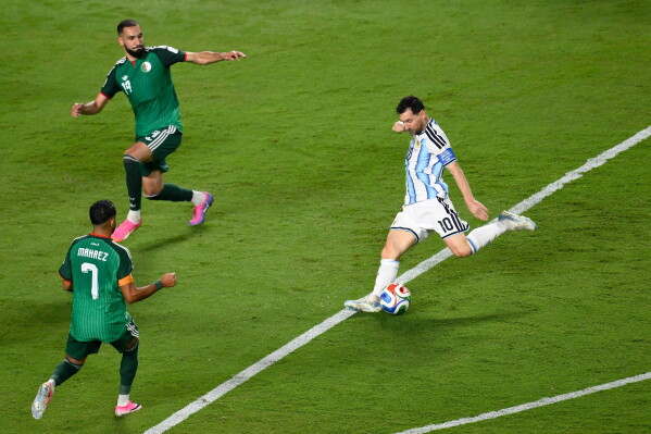 Argentina's Lionel Messi (10) shoots and scores their third goal against Algeria's Riyad Mahrez (7) and Nabil Bentaleb (19) during the World Cup Group J soccer match between Argentina and Algeria in Kansas City, Mo., Tuesday, June 16, 2026. (AP Photo/Reed Hoffmann)