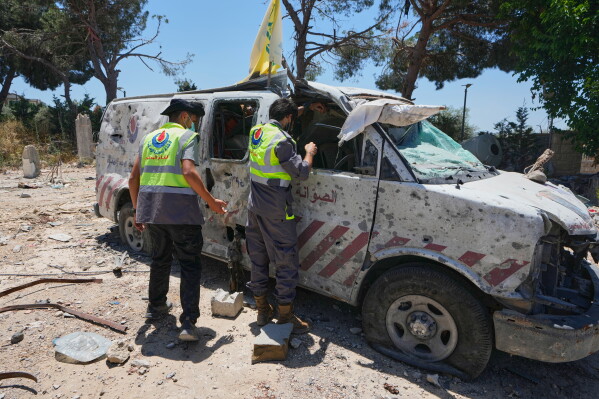 Rescue workers inspect a damaged ambulance belonging to Hezbollah's health unit that was hit in a previous Israeli airstrike in the southern village of Souaneh, Lebanon, Tuesday, June 16, 2026. (AP Photo/Mohammed Zaatari)