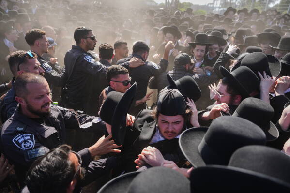 Ultra-Orthodox Jewish men scuffle with police during a protest against military recruitment and call for the release of detained draft resisters outside a military prison near Kfar Yona, Israel, Wednesday, June 17, 2026. (AP Photo/Ariel Schalit)