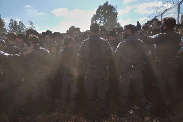 Ultra-Orthodox Jewish men scuffle with police during a protest against military recruitment and call for the release of detained draft resisters outside a military prison near Kfar Yona, Israel, Wednesday, June 17, 2026. (AP Photo/Ariel Schalit)