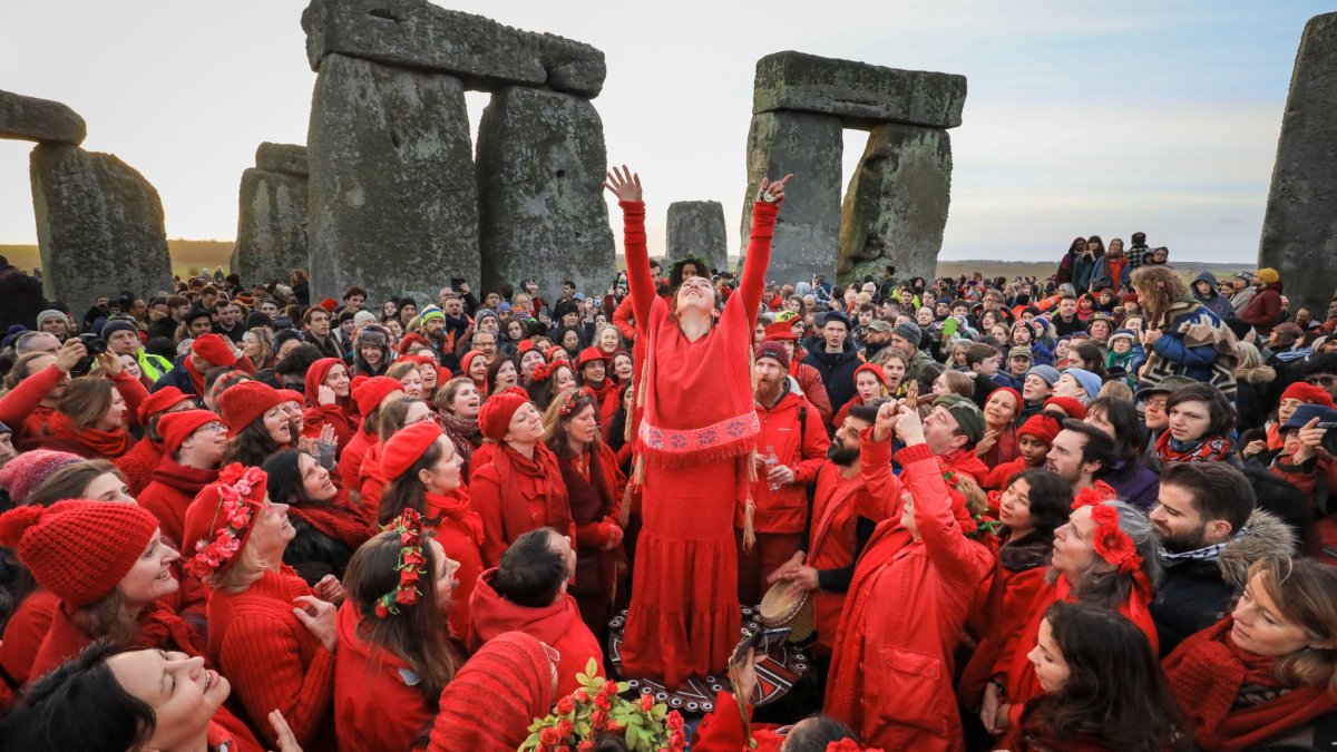 AMESBURY, ENGLAND - DECEMBER 22: Members of the Shakti Sings choir sing as druids, pagans and revellers gather in the centre of Stonehenge, hoping to see the sun rise, as they take part in a winter solstice ceremony at the ancient neolithic monument of Stonehenge near Amesbury on December 22, 2018 in Wiltshire, England. A large crowd gathered at the famous historic stone circle, a UNESCO listed ancient monument to celebrate the sunrise closest to the Winter Solstice, the shortest day of the year. The event is claimed to be more important in the pagan calendar than the summer solstice, because it marks the 're-birth' of the Sun for the New Year. (Photo by Matt Cardy/Getty Images)